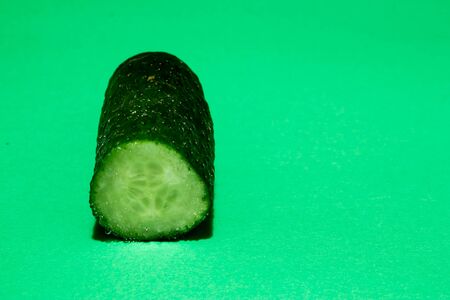 Closeup of a ripe freshly cut in half cucumber on a green backgroundの写真素材
