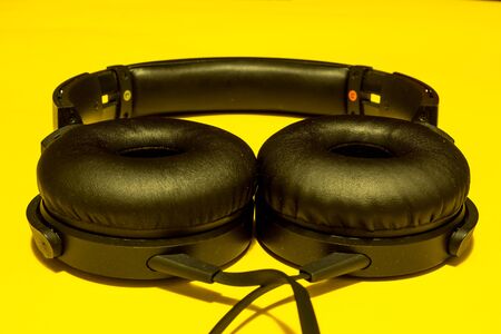 Minimal music concept of a pair of black headphones on yellow backgroundの写真素材