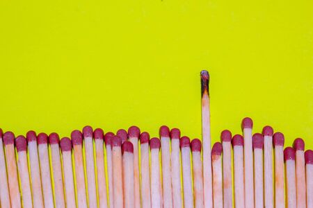 Many matches with one of them burnt standing out from the group. Conceptual imageの写真素材