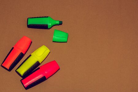 Arranged colored highlighters on brown background while green one having cap openの写真素材