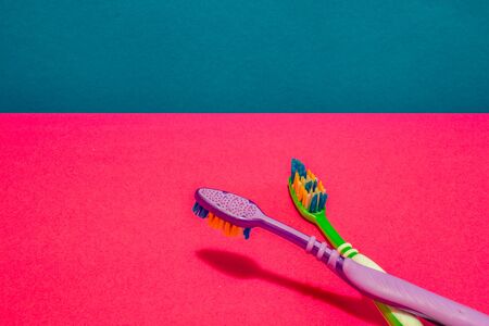 Two tooth brushes on pink and blue background