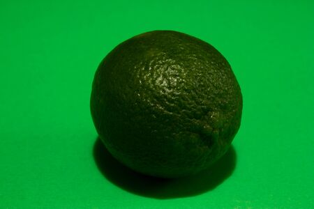 Closeup of a ripe green lime peel texture on a green backgroundの写真素材