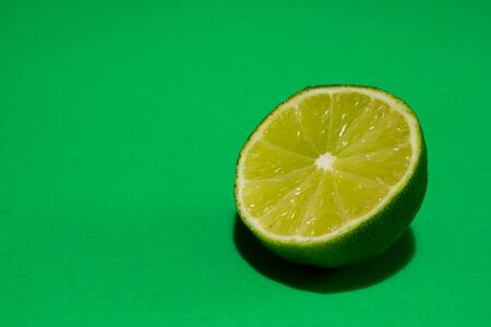 Closeup of a half a ripe lime on a green background with copy spaceの写真素材