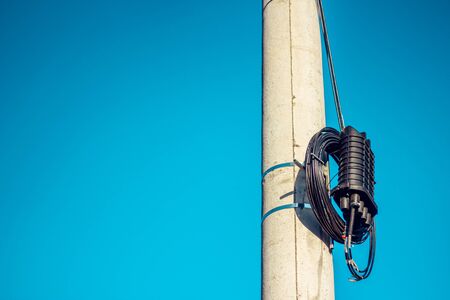 High voltage power cables cluster roll on a tall cement pillar in the city with the sky on the backgroundの写真素材
