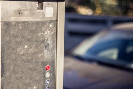 Old fashion metallic closeup of a coin operated parking meter in the city with a blurred background