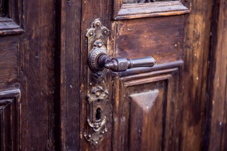 Vintage metal door handle on a solid antique wooden door. Closeup of a retro detailed doorknob
