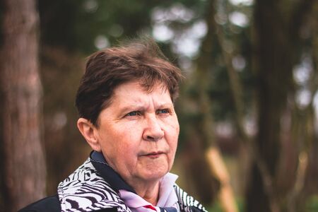 Elder lady closeup standing outside with a sad and worried face â Concept of old person going through anger and depression.の写真素材