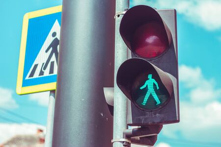 Pedestrian traffic light with green color on a black metallic bar near a crosswalk traffic sign â Public devices and equipment for safety and control â Concept image for go ahead or permissionの写真素材