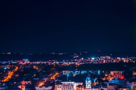 Landscape of city at nighttime with buildings and streets in a blue and violet neon light - Top...