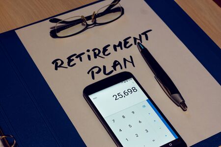 White sheet of paper with the message retirement plan written on it a black pair of glasses a pen and a calculator on top â Concept image for planning money, saving and thinking about the futureの写真素材