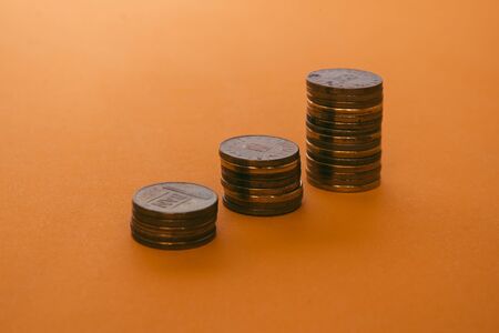 Closeup of three-coin stacks on an orange background â Romanian currency placed in small piles â Concept image for economy growth successの写真素材