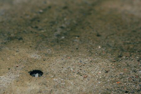 Small hole in the asphalt with a little pebble in it with copy space â Grey background of broken cement with rough textureの写真素材