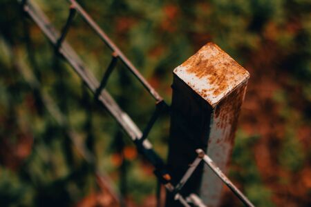 Weathered and old metal fence on a green scenery - Rusty railing with a rough texture and deteriorated surface â Abandoned steel structure used for protectionの写真素材