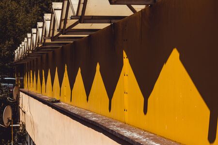 Industrial building with a yellow old wall and a zigzag roof line made from meta â€“ Urban...