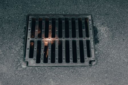 Metallic grid placed on top of the water drain system in the city â Dirty and rusty grill over the public sewerの写真素材