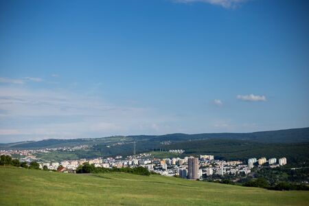 Urban placement in the middle of green hills with a intense blue sky on top â€“ Beautiful...