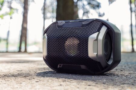 Small black portable speaker placed on the ground in nature â Wireless device for audio playback and listening musicの写真素材
