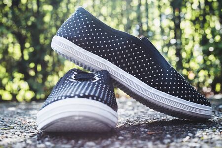 Black sneakers with small white dots placed on the ground with blurred background â€“ Simple...