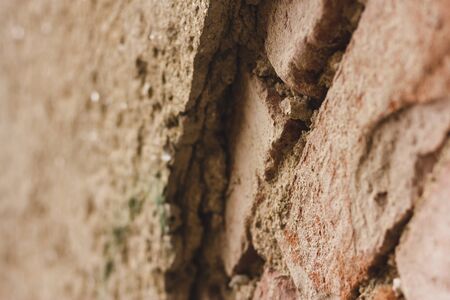 Deteriorated and destroyed brick wall with a rough surface and weathered texture â Old building exterior with broken plasterの写真素材