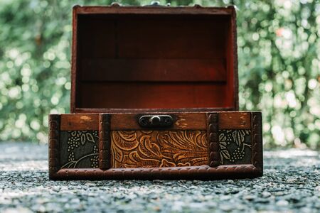 Open wooden chest with beautiful detailed carvings and floral ornament placed on rough ground in nature â Jewelry storing container made from natural materialの写真素材