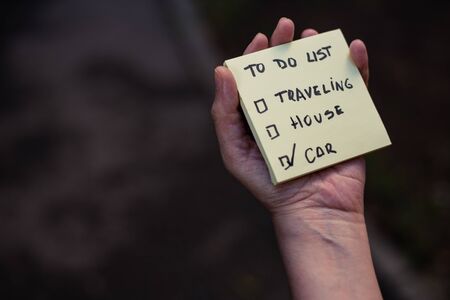 Small yellow reminder held by femaleâs hand outdoor with copy space â Sticky note with the message to do list handwritten on it â Piece of paper with wish listの写真素材