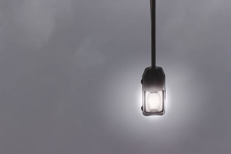 Electric street lamp with metallic case hanging from a cable with copy space â€“ Illumination...
