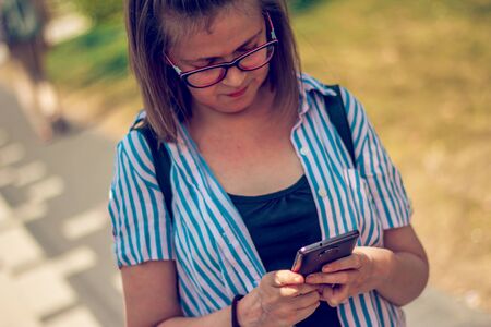 Girl sending a text message with backpack on her backの写真素材