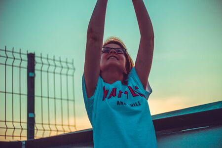 Girl with hands up high feeling happy. Woman enjoying the winning with sunset in the background