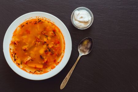 Bean soup with sour cream and silver spoon â Food background with seasonings and copy space on dark textured slateの写真素材