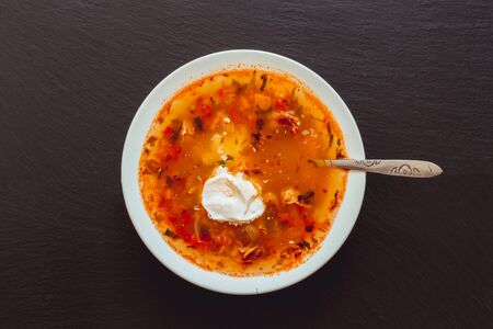 Bean soup with sour cream in the center of a dark ardesia stone â Food background with meal and seasoning on blackの写真素材