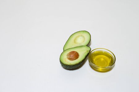 Avocado oil with half avocado cuts on white background with copy space â Natural organic ingredient made from green tropical fruit used as an aliment of cosmeticの写真素材
