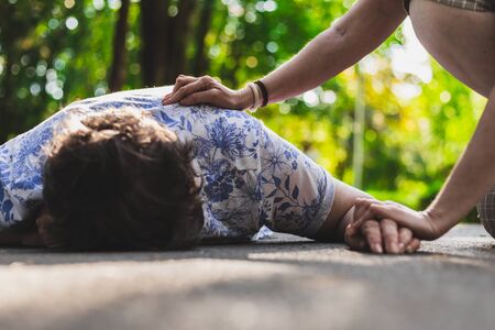 Old woman fell on the ground â Elder lying on the street while a teenager is checking up on herの写真素材