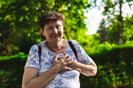 Hand on the chest of a happy cute smiling woman â Senior lady feeling kindness and loved in the natureの写真素材