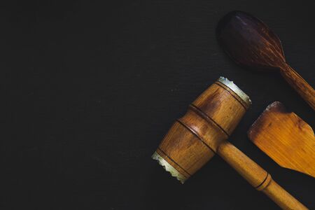 Rustic kitchen tools in the bottom right corner of a black background with copy space - Used wooden...