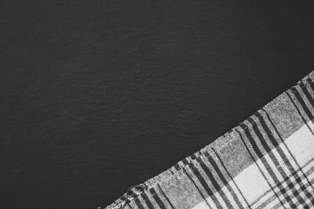 Black and white plaid towel placed in an angle in the bottom right corner of a black background -...