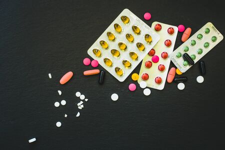 Pills, capsules and blisters of different colors and shapes placed on black background - Pharmaceutical industry background with drugs - Concept image for health careの写真素材
