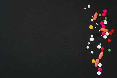Pills and tablets on black background with copy space - Vitamins and painkillers to consume for sicknessの写真素材