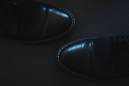 Black leather men shoes with round tips on dark background - Businessman stylish footwear with thick seams on stone textured surfaceの写真素材