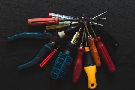 Diverse manual tools heap for home maintenance and work  purpose with a top view on wood. Assortment of  hand  vintage equipment closeup over black board.の写真素材
