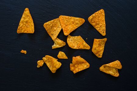 Tortilla chips made of corn spread over a dark table - Healthy snack with salt on a black textured background surfaceの写真素材