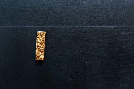 Single protein bar placed on a dark background with copy space â Energy supply snack made from natural ingredients â Sweet and tasty cereal snackの写真素材