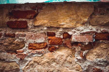 Damaged red brick wall with aged plaster of a building exterior â Vintage architectural background with broken facadeの写真素材