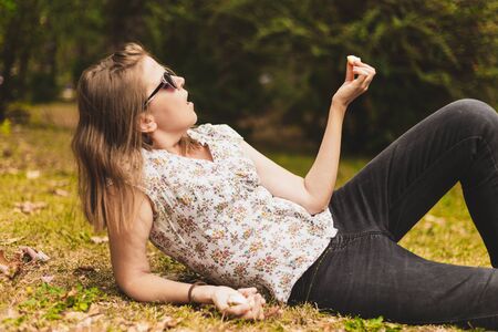 Woman holding garlic clove used as healthy spice in the kitchen - Casually dressed girl with brown hair lying on the grass with fresh and nutritious vegetableの写真素材