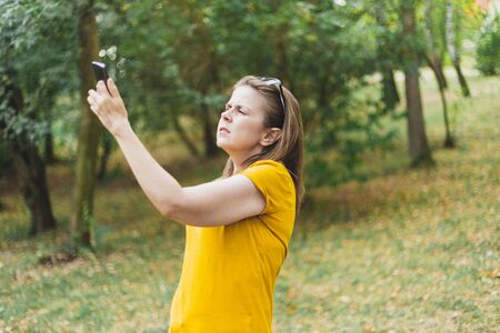 Young woman lost in the forest checking mobile phone signal - Confused and upset cute girl walking in the woods while looking for a way out using a wireless deviceの写真素材