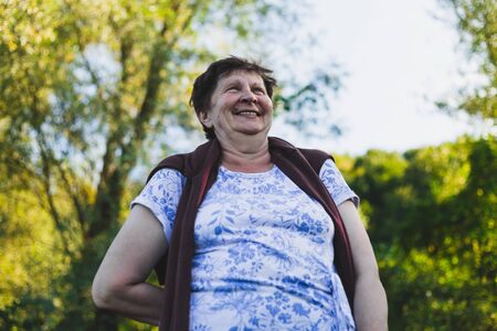 Happy laughing senior woman walking in nature - Portrait of a beautiful smiling old lady having fun and feeling good outdoors - Elderly person with balanced lifestyleの写真素材