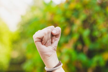 Woman holding strong and powerful fist outdoors - Hand gesture of confidence and successの写真素材