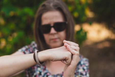 Beautiful young woman holding her fist on her palm outdoors - Pretty girl making hand gestures in sign of strength in the park - Concept image for woman powerの写真素材