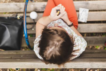 Woman holding colorful pills while sitting on a bench in the park - Casually dressed girl taking...