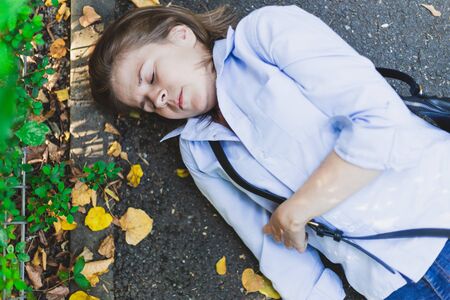 Lying fainted sick woman with heart problems outdoors - Epileptic woman fallen on the ground after seizure caused by stress - injured young female on the street after accidentの写真素材