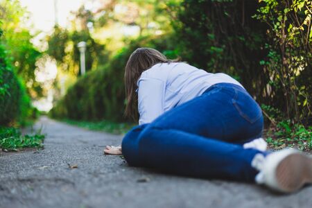 Fainting woman lying on the ground while having heart problems outdoors - Lonely young female fallen...